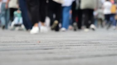 Akşam ışığında yürüyen yayalarla dolu işlek bir şehir kaldırımının yakın görüntüsü.