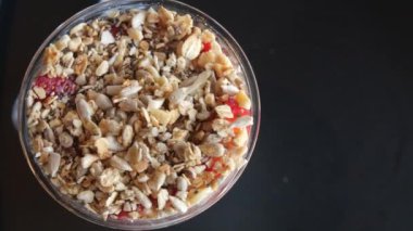 Koyu arkaplanda taze çilekle kaplı lezzetli bir kaşık dolusu gevrek gevrek.