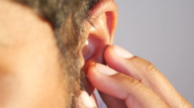 Genç adam acı veren kulağına dokunuyor.