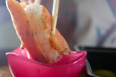 Lezzetli bir karides, canlı pembe bir sosa batırılmaya hazır yemek çubuklarında ustalıkla tutulur.