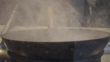 Buharlı suyla dolu büyük bir tencere aşçılık hazırlığı sürecini gözler önüne seriyor.