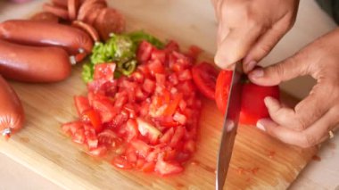 Köy ahşap kesim tahtası yüzeyinde domatesleri ustalıkla doğrayan bir birey.