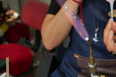 Yetenekli bir zanaatkar, cam üfleme sürecinde alev feneriyle cam şekillendirir..