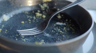 Kalıntıları ve zarif bir çatalı olan beyaz bir tabak. Bitmiş bir yemek deneyimini simgeliyor.