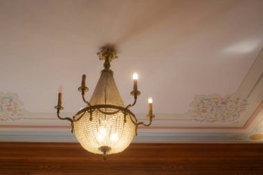 Göz kamaştırıcı bir klasik avize zarafetle dekore edilmiş tavanı zarafetle aydınlatıyor.