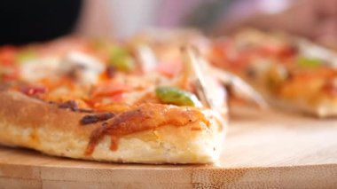 Köy tahtasında sıcak servis edilen, malzemeli lezzetli bir pizzanın yakın çekimi.