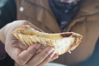 Bir el, lezzetli, erimiş peynirle dolu sıcak ve taze bir tost sandviç tutuyor.