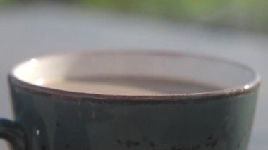 Bir kahve fincanının huzurlu ve huzurlu yakın plan görüntüsü, güzel doğal ışıkta hafifçe buharlaşır.