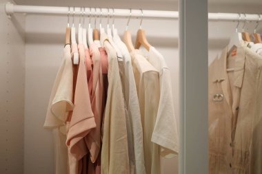 Zarif pastel kıyafetlerin yumuşak ve rahatlatıcı tonlarda sergilendiği düzenli bir dolap.