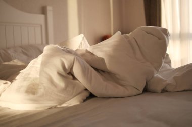 Yapılmamış, dağınık bir yatak, yeşil bir yatak başlığıyla çelişen güzel çiçekli bir yatak.