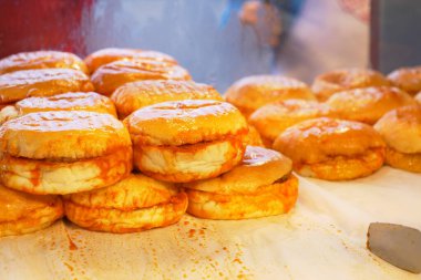 Canlı bir fırın vitrininde güzelce istiflenmiş sıcak jöleli donut seçimi.