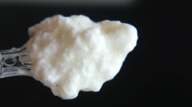 Siyah arka planda plastik bir kaşıkta taze yoğurt. ,