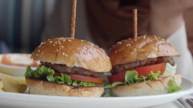 Lezzetli ve lezzetli mini burgerler, taze marul ve olgun domatesle güzelce servis edilir.