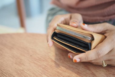 Kırsal ahşap bir yüzeyde el ele tutuşan şık bir cüzdanın yakın plan görüntüsü, tasarımını gösteriyor.