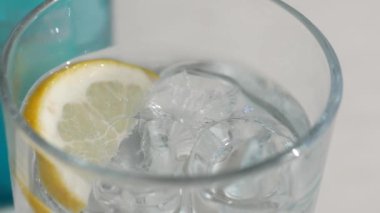 Buzlu soğuk bir bardak serinletici suyun ve mükemmel bir içecek olarak bir dilim limonun tadını çıkar.