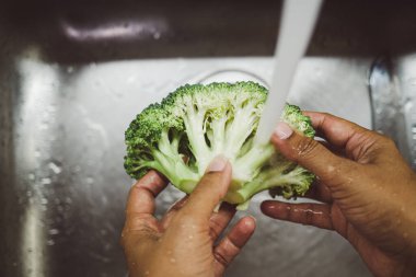 Sağlıklı ve besleyici bir yemek hazırlamak için mutfak lavabosunda taze brokoli temizliyorum.