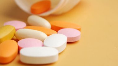 Bir şişeden yüzeye dökülen vitamin ve ilaçlardan oluşan renkli bir karışım.