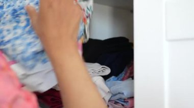  Beyaz bir dolabın çekmecesinde bebek kıyafetleri saklayan bir kadın..