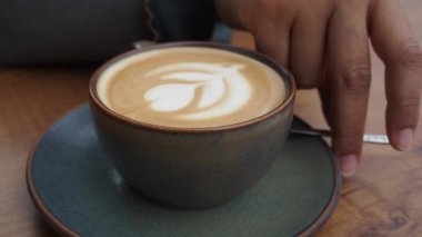 İnsan, kaşıkla kahve karıştırır.