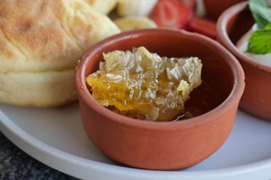 Lezzetli bir kahvaltı için sıcak bisküviler ve taze böğürtlenlerle bal peteğinin tadını çıkarın.