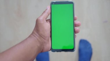Boş yeşil ekranlı akıllı telefonu tutan bir el, dijital içerik kullanımı için ideal.
