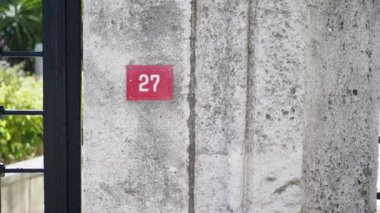 Pürüzlü beton bir duvarda belirgin bir şekilde görünen 27 sayısının detaylı bir yakın çekim görüntüsü