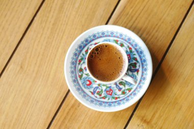 Geleneksel bir çiçekli fincanda servis edilen dumanı tüten Türk kahvesi kareli bir masa örtüsü. Kültürel, aşçılık ve ev temalı projeler için mükemmel..