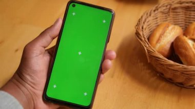 Bir el, canlı yeşil ekranlı akıllı telefonu kavrıyor. Model oluşturma için mükemmel.