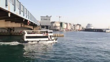 Arka planda çarpıcı bir silueti olan sakin sularda bir tekne sorunsuzca ilerliyor.