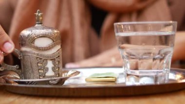 Geleneksel bir çiçekli fincanda servis edilen dumanı tüten Türk kahvesi kareli bir masa örtüsü. Kültürel, aşçılık ve ev temalı projeler için mükemmel..