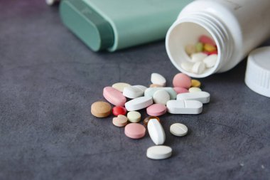Bir şişeden yüzeye dökülen vitamin ve ilaçlardan oluşan renkli bir karışım.