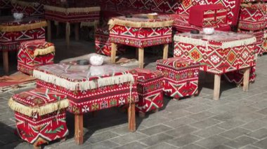 Geleneksel bir kafede açık hava koltukları desenli yastıklar, kırsal ahşap masa ve sandalyeler.