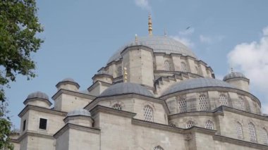 Büyük kubbeleri ve renkli gökyüzünün altında uzun minareleri olan güzel bir cami.