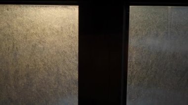 Yumuşak ışıklandırmayla güzelce aydınlatılan sisli cam pencerelerin yakın görüntüsü