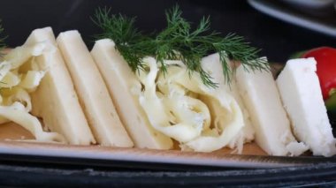 Peynir dilimleri, şifalı otlar ve servis tabağında kiraz domatesleri..