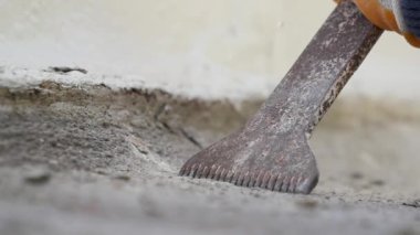 Yetenekli bir işçi, beton yüzeyi yenilemek için kazıma aletini titizlikle kullanır.