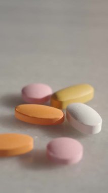 Bir şişeden yüzeye dökülen vitamin ve ilaçlardan oluşan renkli bir karışım.