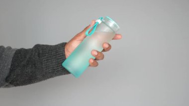 Gri Arkaplan Karşısında Yeniden Kullanılabilir Su Şişesi Tutan Kişi,