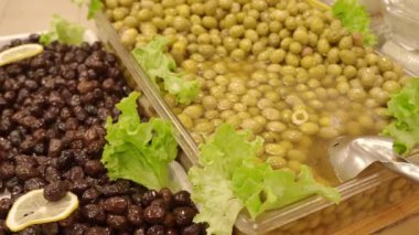 Lezzetli bir yemek için taze marulla servis edilen canlı yeşil ve siyah zeytinlerin tadını çıkarın.