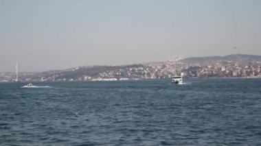 Boğaz 'ın tekneli sakin manzarası ve arkasında çarpıcı İstanbul silüeti
