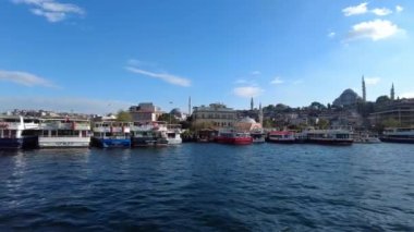 Canlı bir liman manzarası, çarpıcı tarihi mimariyle birlikte bir dizi tekne sergiliyor.