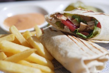 Lezzetli tavuk dürümünün tadını çıkarın. Kızarmış patates kızartması ve nefis bir yemek için lezzetli bir sos.