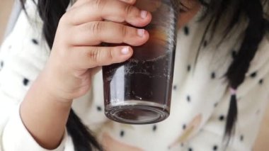Neşeli bir çocuk güneşli bir kafede otururken soğuk ve ferahlatıcı bir içecek yudumluyor.