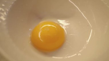 Parlak sarı bir yumurta sarısı temiz, el değmemiş bir yumurta beyazının içinde duruyor, bir kasede yakalanmış.