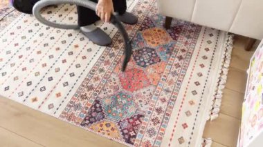 Kadınlar halıyı süpürgeyle temizliyor.