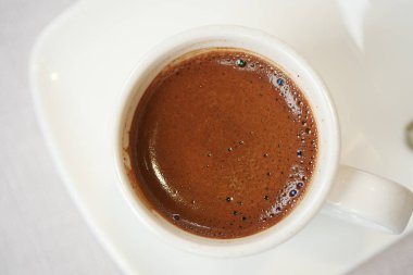 Genel bir perspektif, zengin, koyu kahve dolu güzel bir kahve fincanı yakalar.