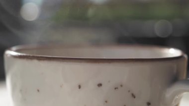 Sıcak bir ortamda sıcaklığı ve rahatlığı çağrıştıran buharı tüten seramik bir kahve bardağının yakın çekimi. Rahatlamayı, sıcaklığı ya da rahatlatıcı bir sabah rutinini göstermek için mükemmel.. 