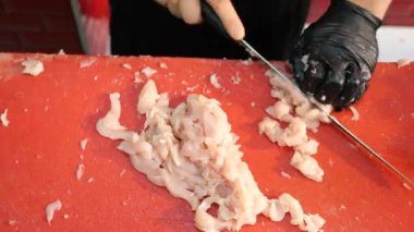 Taze ve lezzetli deniz ürünleri titizlikle canlı kırmızı bir kesme tahtasıyla doğranır.
