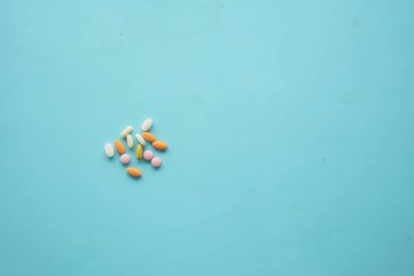 Parlak mavi bir yüzey üzerinde çeşitli vitaminler ve ilaçlar sergilendi,