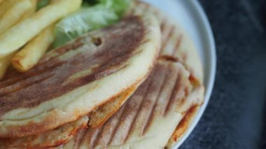 Kızarmış patates ve taze yeşilliklerle birlikte lezzetli ve lezzetli bir sandviçin tadını çıkarın.